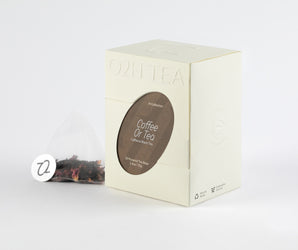 Packaging of Caffeine Black Tea displayed with a tea bag containing rich, dark leaves, ready for brewing.