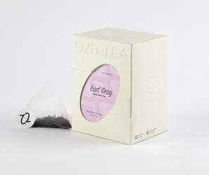 Classic Earl Grey Tea in distinctive packaging with a visible tea bag showing fine black leaves and bergamot orange zest.