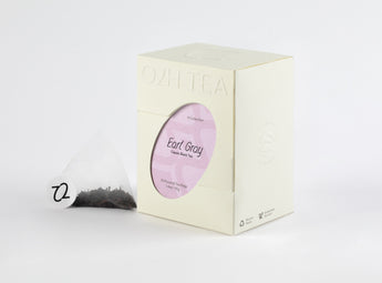 Classic Earl Grey Tea in distinctive packaging with a visible tea bag showing fine black leaves and bergamot orange zest.