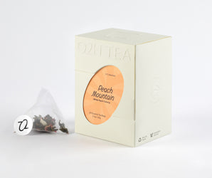 A box of White Peach Oolong Tea displaying with a tea bag filled with aromatic oolong tea leaves and peach pieces.