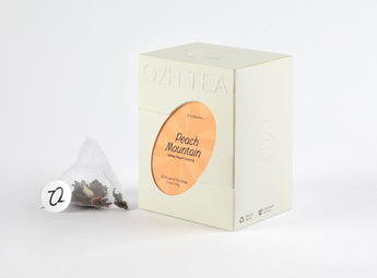 A box of White Peach Oolong Tea displaying with a tea bag filled with aromatic oolong tea leaves and peach pieces.