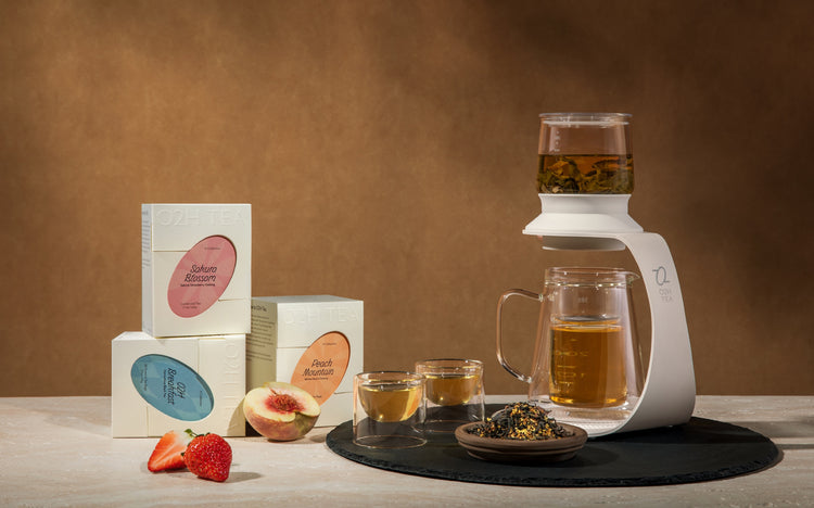 An inviting arrangement of O2H TEA's White Peach Oolong, Breakfast Tea, and Sakura Oolong, steeping in a clear teapot, with loose leaf tea and cups ready for a refined tea tasting experience.