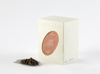ashi Aroma Phoenix Oolong Tea box displayed next to a sample of its aromatic, tightly rolled oolong tea leaves on a silver plate.